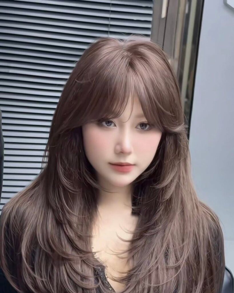Long layered haircut with a soft curtain fringe in warm ash brown, cut at Nhat Tam Hair Salon in Hanoi