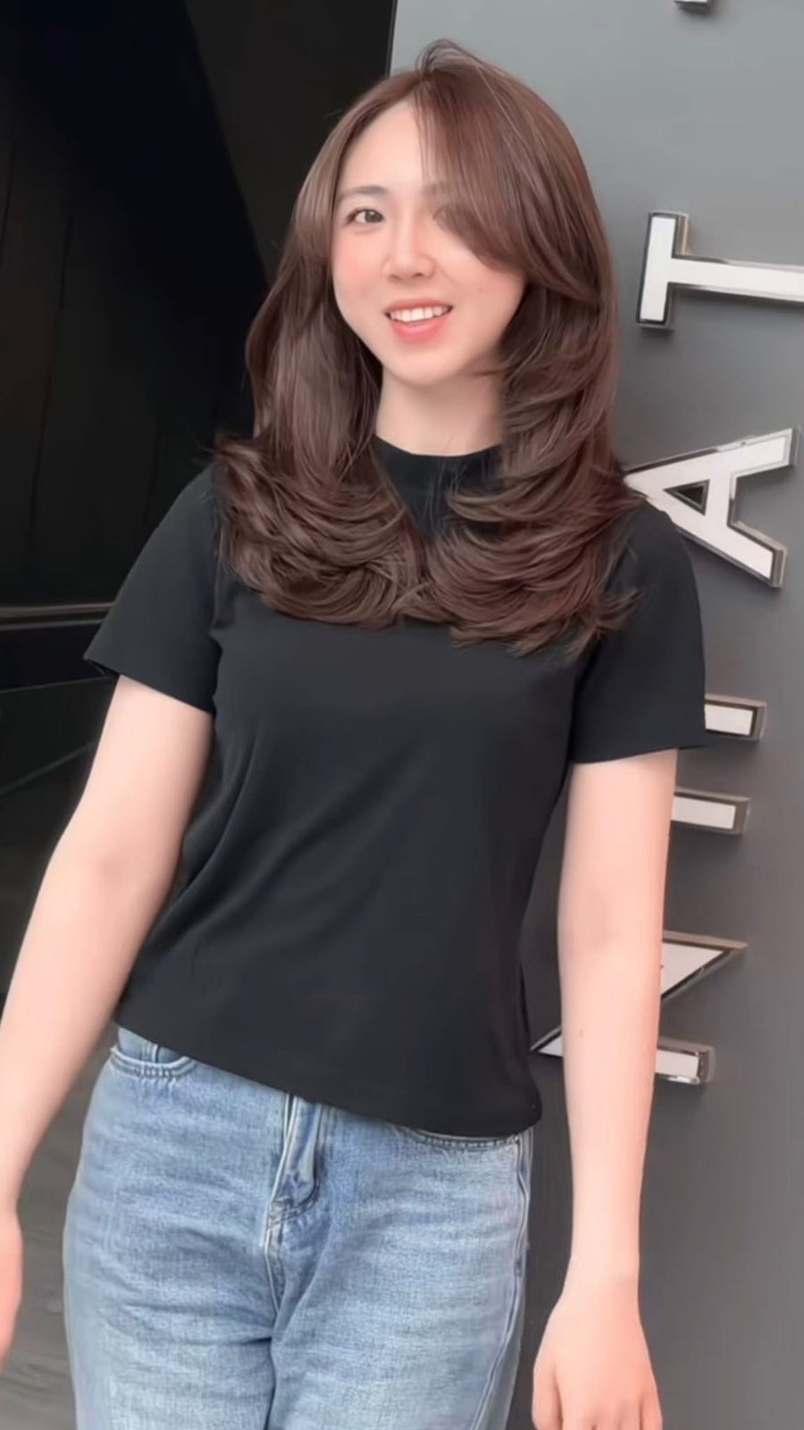 Mocha brown medium length layers with curled ends on a client outside Nhat Tam Hair Salon in Hanoi