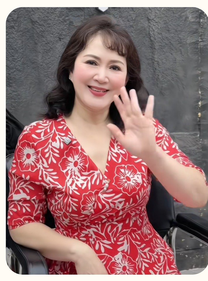 People’s Artist Minh Hoa smiling in a red floral dress after a soft wave perm at Nhat Tam Hair Salon in Hanoi