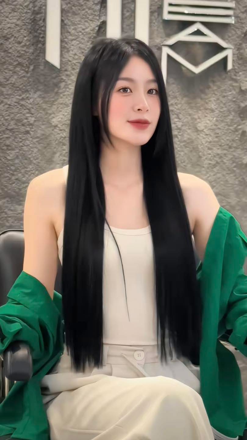 Long straight hair result photographed in front of the Nhat Tam salon wall