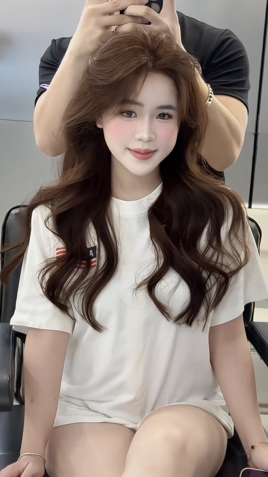 Stylist lifting the crown to check that a brown colour is even from root to end in Hanoi